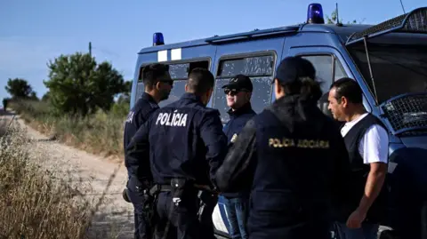 AFP via Getty Images Five Portuguese Criminal Investigation Police investigators stand in a road