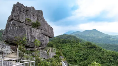 Getty Images A large limestone boulder, with a footpath leading to it, against the backdrop of Masungi's lush rainforest. 