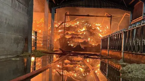 A large amount of hay on fire in a barn