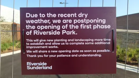Paul Emerson A burgundy sign attached to a fence at Riverside Park reads: Due to the recent dry weather, we are postponing the opening of the first phase of Riverside Park.
This will give new planting and landscaping more time to establish and allow us to complete some additional improvement works. We will share a new opening date as soon as possible.
Thank you for your patience and understanding.
Riverside Sunderland. 