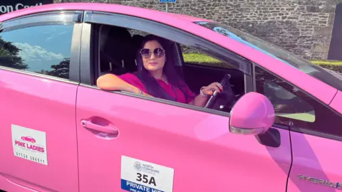 BBC/JULIA LEWIS Amberine Nawaz sitting in pink taxi