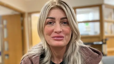 Chantal Harrison looking at the camera. She has long blonde hair and is wearing a brown hoodie.