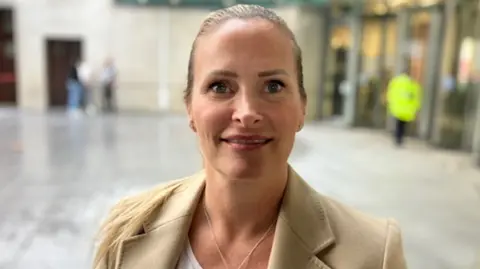 Trudi Dawson, director of Doula UK, smiling at the camera. She is wearing a brown coat