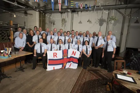 RLNL Portishead Volunteers in uniform at RNLI Portishead pose with a RNLI flag