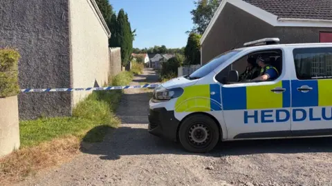 A police van is seen in front of police tape
