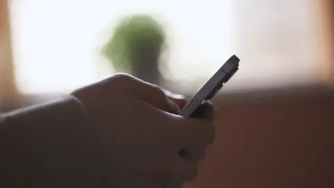 A close up of a young man's hand holding a mobile phone.