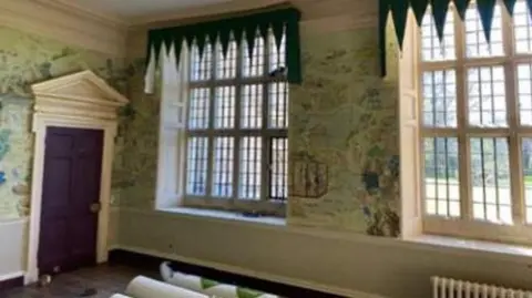 Peter Davison The interior of a highly-decorated room with large twelve-square windows and elaborate wallpaper. Cornices can be seen in the corner of the room. 