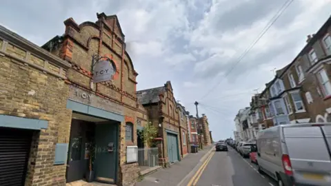 A brick building on a terraced, residential street. The signage on the building reads TCY.