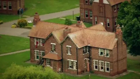 Cottage building with gardens surrounding and paths to the next cottages - HMP Styal occupies former buildings of Styal Cottage Homes, which opened as an orphanage in 1898