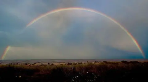 Matt Daymond  A rainbow above a beach.