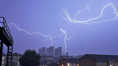 BBC Weather Watchers / Vic fork lightning fills the darkened sky with some lightning hitting some high rise buildings in the distance