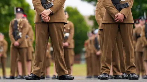 Getty Images A stock image shows the legs and feet of junior soldiers lining up and holding guns at the Army Foundation College in 2015