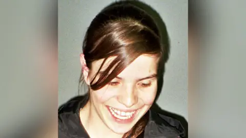 Picture of Lorraine Thorpe. She is looking down and smiling with her hair scraped back from her face. 