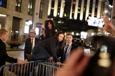 Reuters Maria Corina Machado jumps over barricades outside the Grand Hotel in Oslo to greet cheering supporters as security looks on.