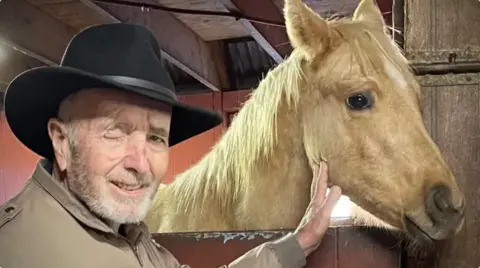 Lind Family/GoFundMe A man poses with a horse. The man is wearing a hat and missing his right eye.