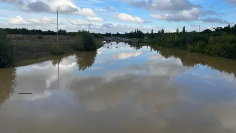 Tony Fisher/BBC The water levels on the A421 were so high before that you can only just see the top of the roadside pumping station 