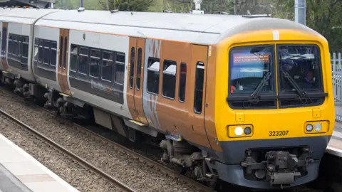A yellow West Midlands Railway train on the tracks
