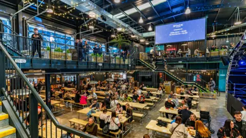 Stack Leisure A foodhall with people sitting down at tables, in an open double-floored room. 