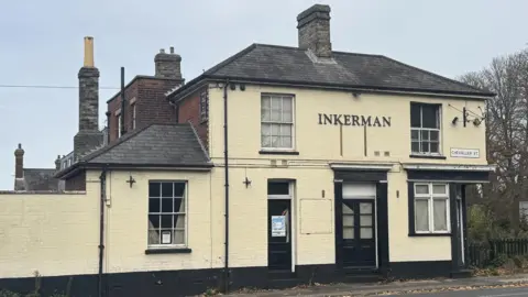 A photo of The Inkerman pub building taken from the opposite side of the road. The cream building is closed up with little sign of life.