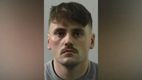 Mugshot of James. He has a neat brown moustache and short brown hair