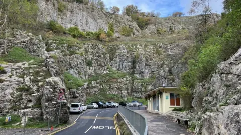 Cheddar Gorge with cars parked along the road with the rocks above