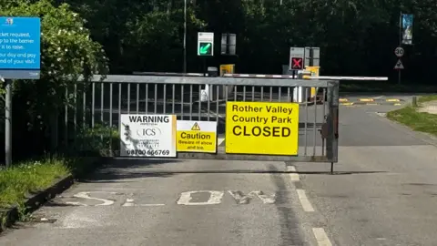 General view of the entrance to Rother Valley Country Park, with a large yellow sign saying the park is closed.