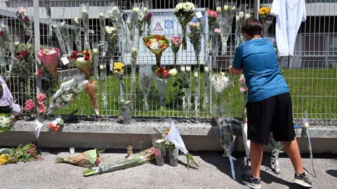 AFP A boy hangs flowers on the fence of his school