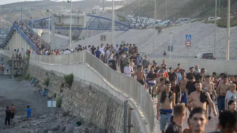 Dozens of migrants walking on a coastal path 