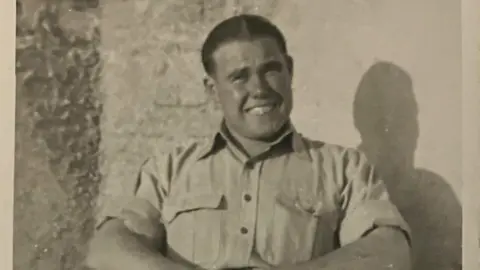 Family handout A black and white image showing Fred in a light shirt, sitting down and smiling as he looks at the camera.