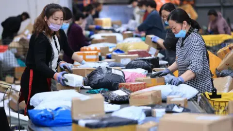 Getty Images Karyawan mengurutkan parsel ekspres pada jalur penyortiran otomatis di pusat distribusi di depan festival perbelanjaan ganda 11 pada 4 November 2024 di Lianyungang, Provinsi Jiangsu di Tiongkok. 