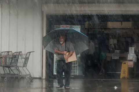 Getty Images A man walks out of a shop carrying supplies