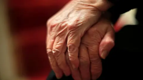 A picture of hands resting on top of one another on someone's knee.