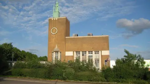 The historic print works in Watford. It is a sunny day and the building is surrounded by greenery.