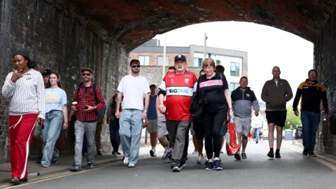 Getty Images Gloucester Rugby fans walk under an underpass on their way to watch their team at Kingsholm