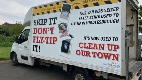 A van with writing on the site warning people not to fly-tip