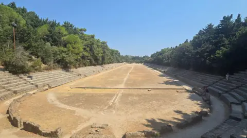 Ben Moorhouse An ancient athletic stadium, surrounded by trees.