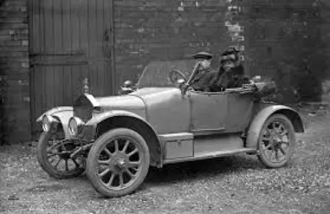 HistoryPoints.org/Сhronology of cars To the left is a Singer 10hp advert, extolling its prowess at the Colwyn Bay Trials and the nearby ascent of the Great Orme. To the right is a 1913 example of the same car, with a snub bonnet and radiator grill with chrome surround. On board are a  couple, the man is in a flat cap and tweeds and a woman wearing a hat and fur coat 