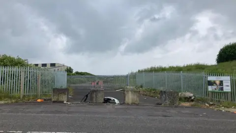 Grey skies and metal fencing around some industrial scrubland 