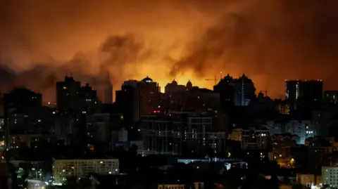 An explosion of a drone lights up the sky over the city during a Russian drone strike