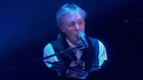Sir Paul McCartney playing on a piano 