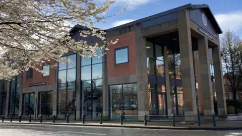 The exterior of Beverley Magistrates' Court which is a modern two-storey building with constricted form red brick, with large windows and a pitched roof with three stone columns at the front 