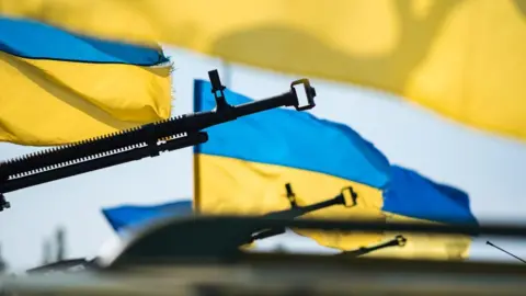 Roman Naumov Ukrainian flags blowing in the wind and guns pointed upwards