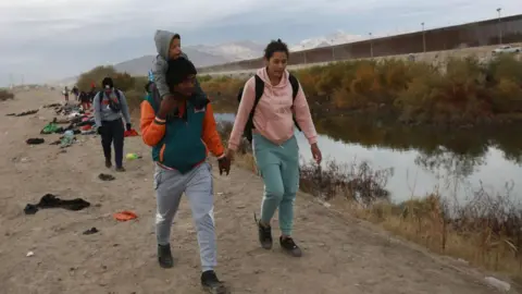 Getty Images A woman walking with a man and a child on the Mexico-El Paso border.
