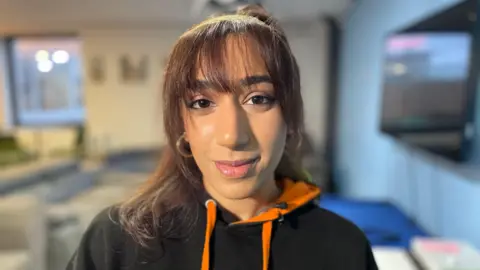 Ameerah is wearing a black and orange hoodie