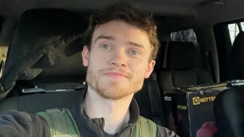 A smiling Chris Parry in a vehicle.
