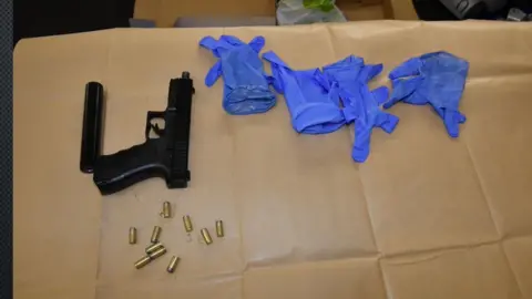 Nottinghamshire Police A black handgun and silencer with bullets and four gloves