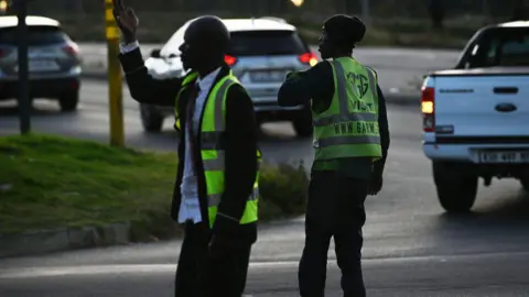 Getty Images Zelfbenoemde verkeersleiders regelen het verkeer om geld te verdienen met de fooien van automobilisten, terwijl verkeerslichten uitgaan tijdens een black-out, plaatselijk bekend als load shedding, in Johannesburg, Zuid-Afrika, dinsdag 23 mei 2023.