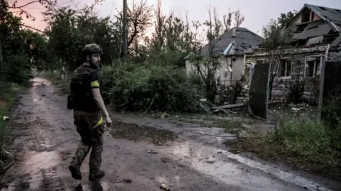 OLEG PETRASIUK/24TH MECHANIZED BRIGADE HANDOUT/EPA-EFE/REX/Shutterstock A Ukrainian serviceman stands in a road looking back, with houses to the side
