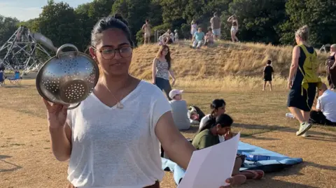 Dan Bater/BBC A woman in a white T-shirt holds a colander.