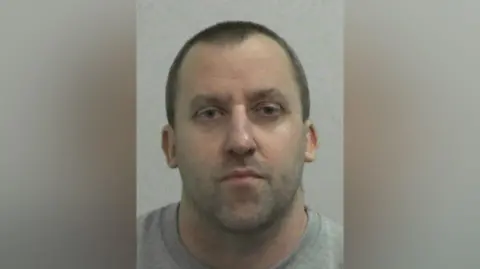 NEROCU Mugshot of Follos. He has short shaved hair and stubble